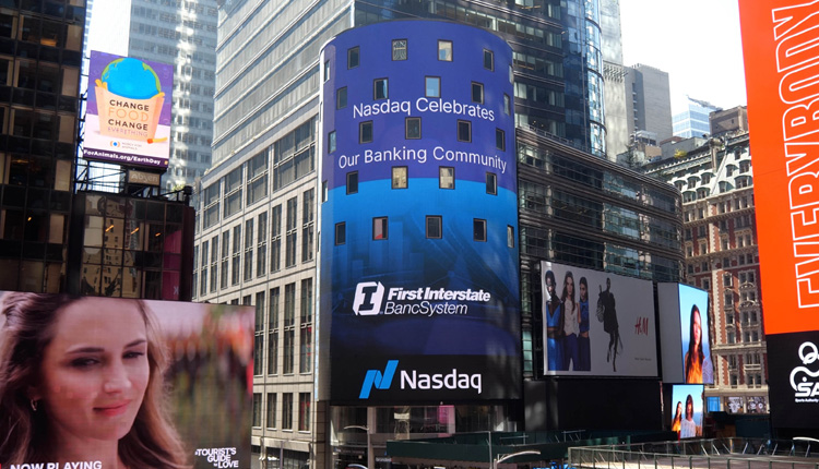 The Nasdaq Tower in Times Square displays the First Interstate Bank logo and text stating, “Nasdaq celebrates our banking community.”